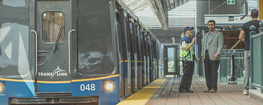 Passenger chatting with a SkyTrain attendant on an Expo Line SkyTrain platform