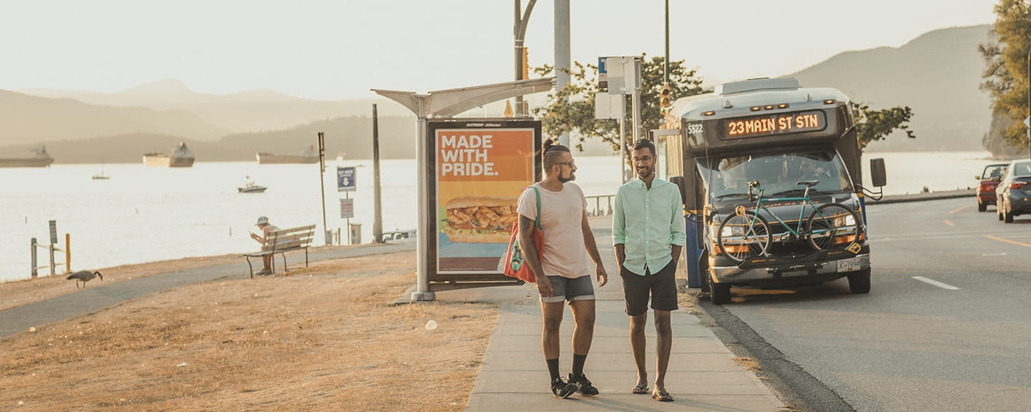 Two men walking away from a shuttle bus at a bus stop