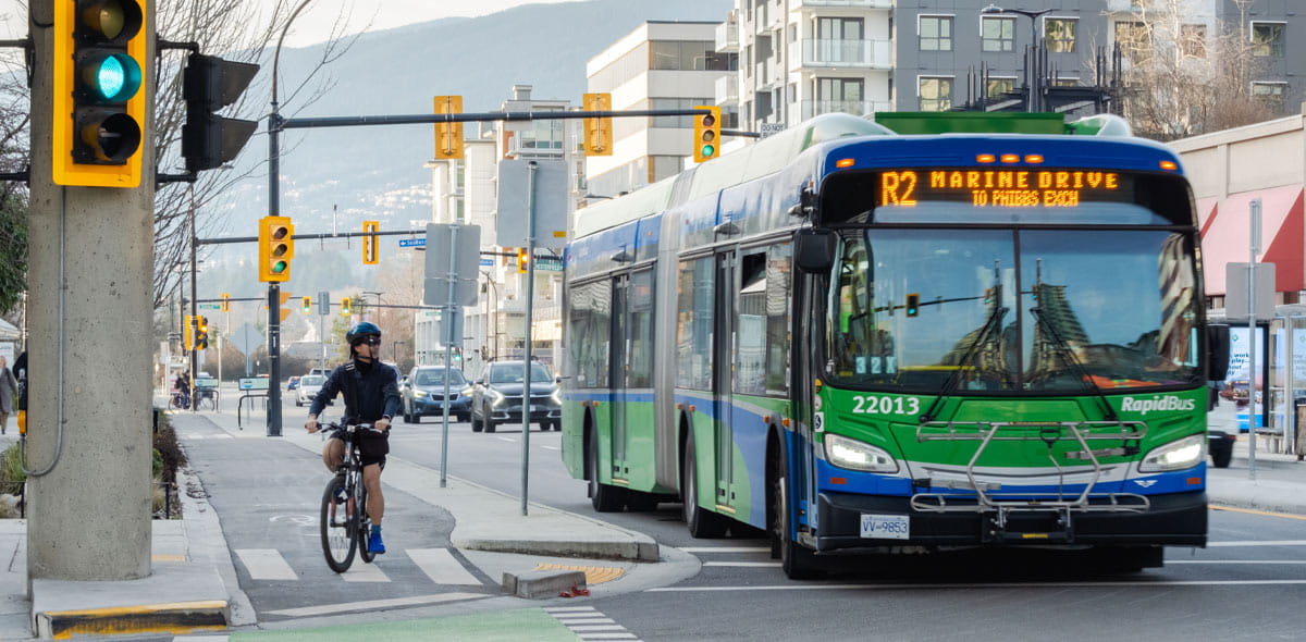 Cyclist and R2 Marine Drive RapidBus to Phibbs Exchange along Esplanade in North Vancouver