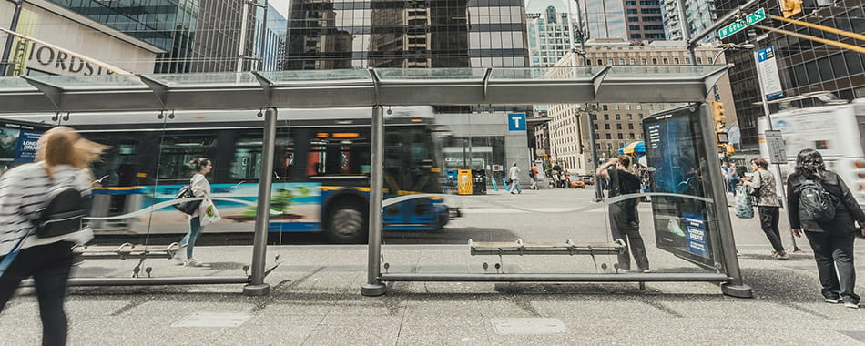 People walking around a bus shelter stop in the middle of downtown Vancouver